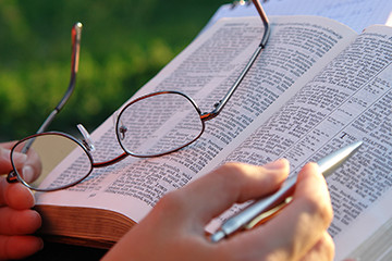 a woman learning how to pray by studying her bible outside