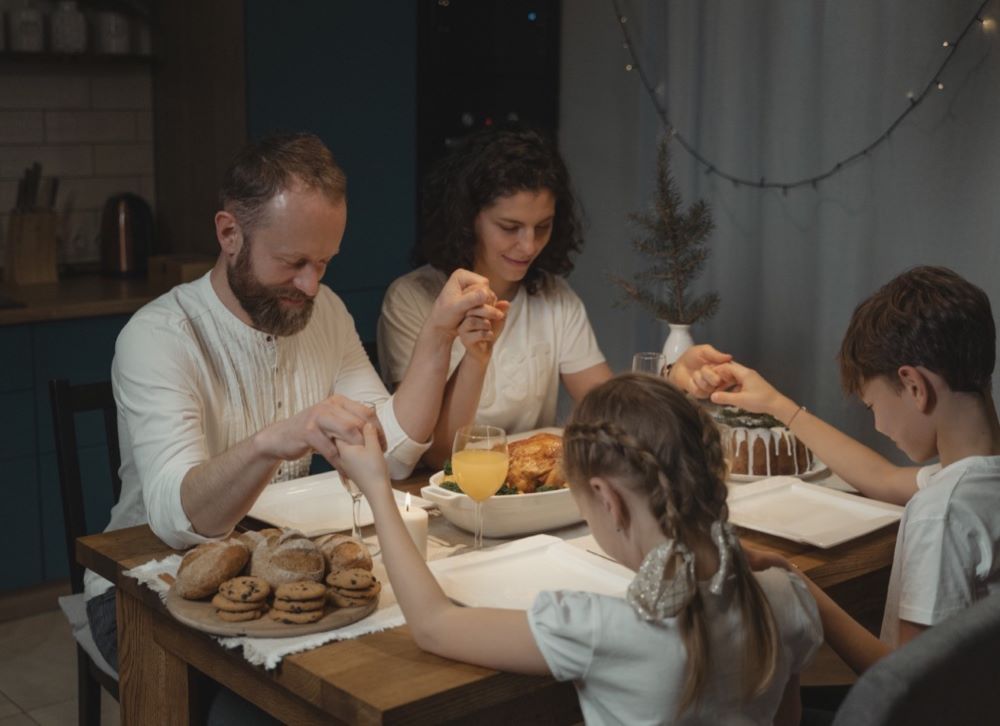 family praying a blessing at dinner