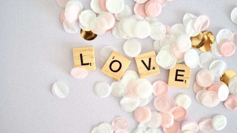 love spelled out on 4 wooden blocks on a table with white, pink, and gold paper representing god's love for you